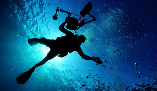 Silhouette of Person Holding Camera in Body of Water thumbnail