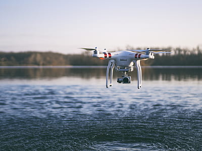 white DJI quadcopter drone flying above body of water thumbnail