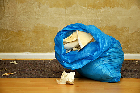 white crumpled paper in blue plastic bag inside brown room thumbnail