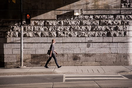 A young caucasian man carrying a messanger bag walking in urban sunlight thumbnail