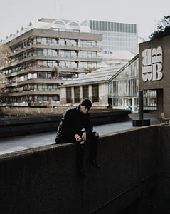 man sitting on the wall near the buildings thumbnail
