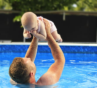 father lifting baby on pool during faytime thumbnail