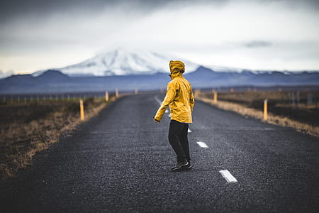 person in yellow hoodie standing on road thumbnail