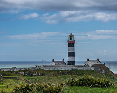 white and black lighthouse near houses during daytime thumbnail