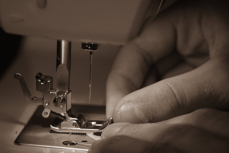 grayscale photo of person using sewing machine thumbnail