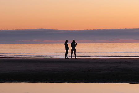 man and woman silhouette stand on seashore thumbnail