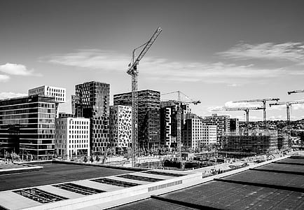 grayscale photo of building crane near high-rise buildings thumbnail