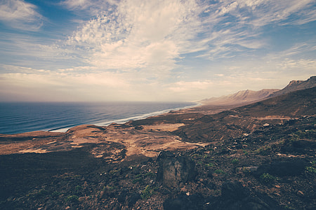 top view photography of mountain near seashore under cloudy sky thumbnail