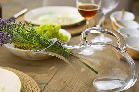 lavender flowers in clear glass pitcher on brown wooden table with dinnerware thumbnail