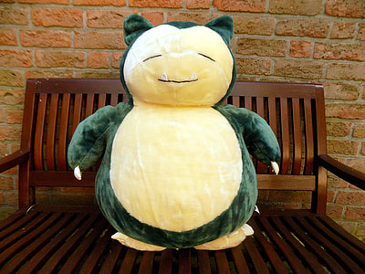 green and yellow animal plush toy on brown wooden bench thumbnail