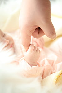 baby holding index finger of person thumbnail