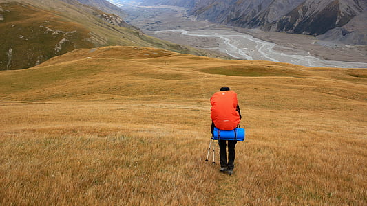 person carrying bag walking on mountain during daytime thumbnail
