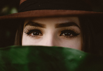 woman wearing black and brown top hat while covering her face with green towel thumbnail
