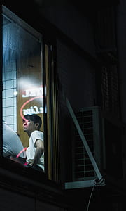 man in white top sitting beside of brown door thumbnail