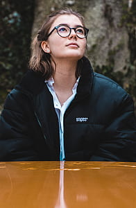 woman looking on top while sitting near brown table thumbnail