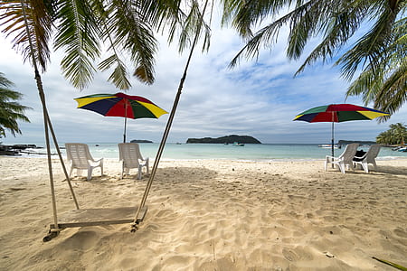 patio umbrellas with chairs near beach at daytime thumbnail