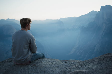 man sitting near cliff during daytime thumbnail