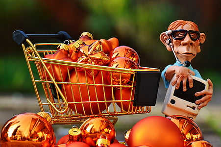 man figurine wearing headset standing beside shopping cart miniature full of baubles thumbnail