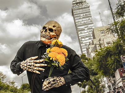 person in skeleton costume holding bouquet of yellow petaled flowers thumbnail