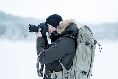 man in black parka hoodie using smartphone thumbnail