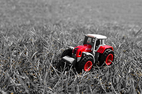 red and black tractor miniature on grass field thumbnail