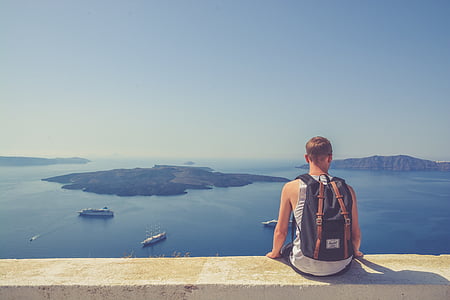 man sitting on concrete surface over body of water thumbnail