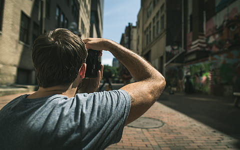 man in gray t-shirt standing on pavement near buildings thumbnail