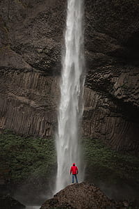 photo of man standing near waterfalls thumbnail