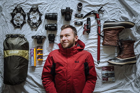 Man Lying on Gray Surface Beside Boots, Rhode Microphone and Coleman Bag thumbnail