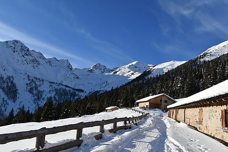 brown concrete house and snow covered mountain under blue sky at daytime thumbnail