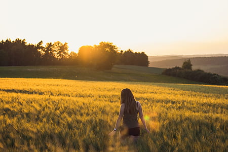 woman walking on grass field during sunset thumbnail
