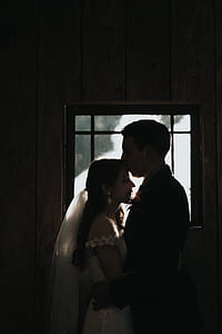 man kissing brides forehead near glass window thumbnail