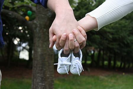 person holding pair of baby's white sneakers thumbnail