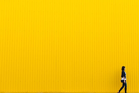 woman walking beside yellow wall thumbnail