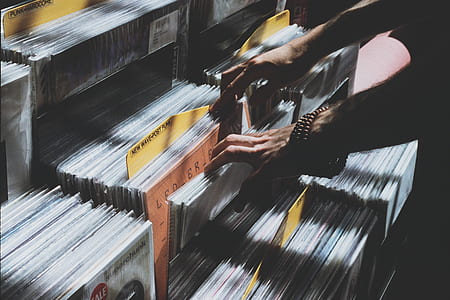 person holding vinyl record disc sleeve on rack thumbnail