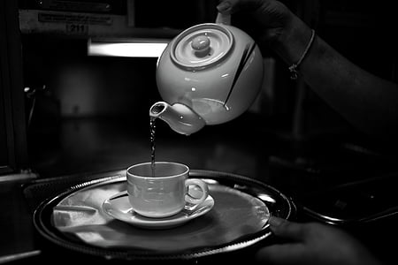 grayscale photography of teapot pouring liquid in white cup thumbnail