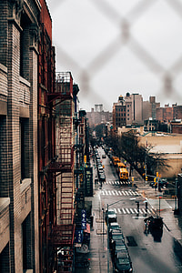wire fence overlooking high rise buildings with cars and bus photography thumbnail