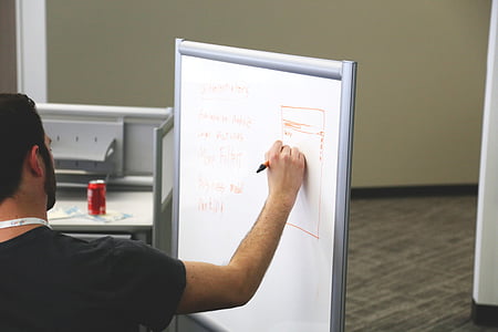 man writing on whiteboard inside lighted room thumbnail