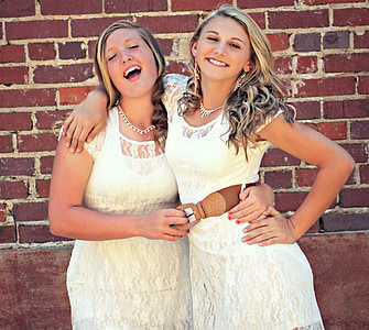 two woman hugging each other near brick wall thumbnail