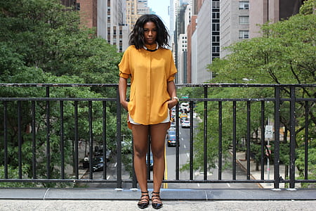 woman in yellow mini dress leaning on black metal baluster thumbnail