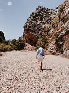 Person Walking Near Rock Formation thumbnail