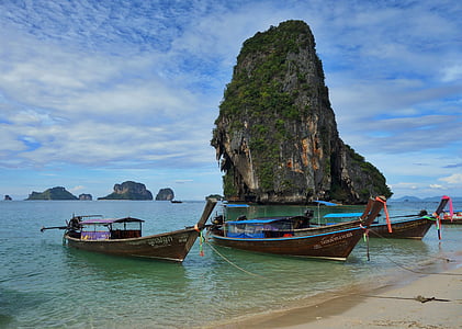 two blue and one brown sail boats on body of water thumbnail