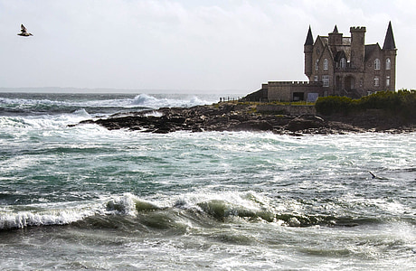 gray concrete castle on an island in ocean during daytime thumbnail