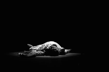 man lying on black surface with spot light thumbnail