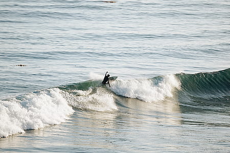 person surfing on sea waves during daytime thumbnail