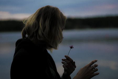 woman looking at flower she's holding thumbnail