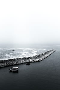 grayscale photo of boat near concrete barrier thumbnail