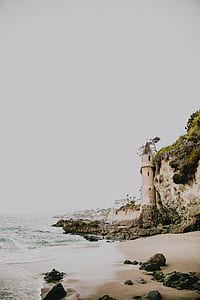 white sand beach with lighthouse on seashore thumbnail