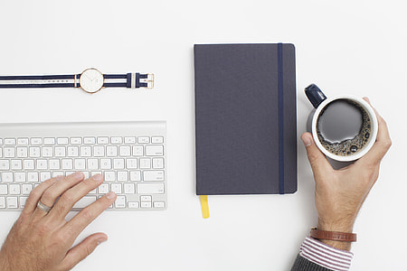 man holding on his right hand a blue ceramic cup filled with coffee and on his left hand a white wireless keyboard thumbnail