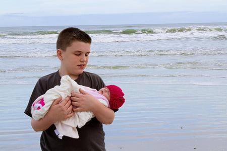 boy carrying baby on the beach thumbnail